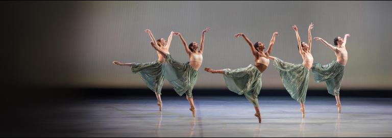Ballet dancers in green skirts dance in unison.