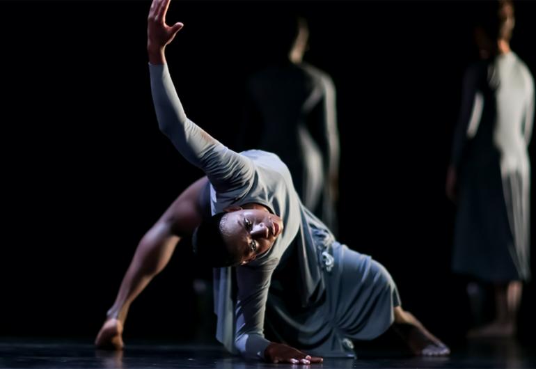 Morris in a back bend with one arm raised up and head looking at the viewer