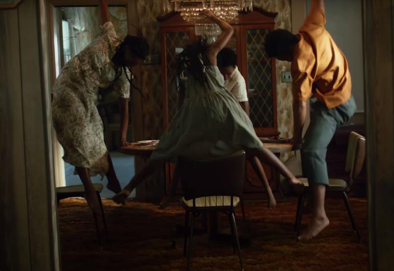 Still frame of dancers jumping around a dining table from the music video for Sufjan Stevens’ Sugar