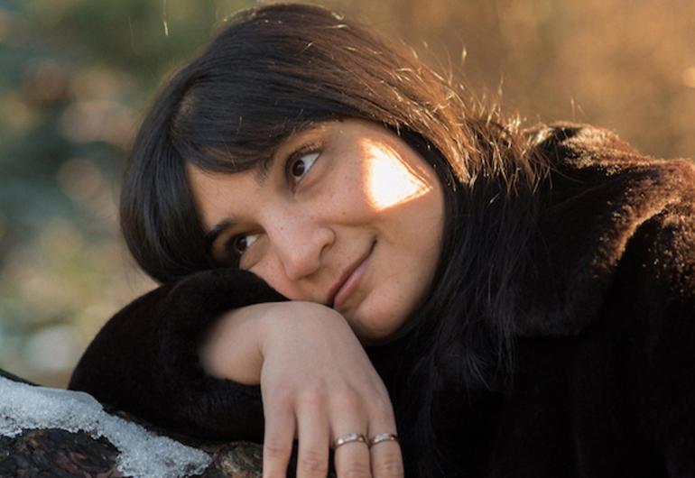 Sarah Davachi resting her head on her arm in the sunlight