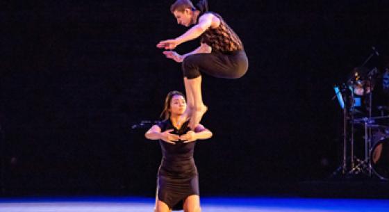 Two dancers in front of a dark backdrop