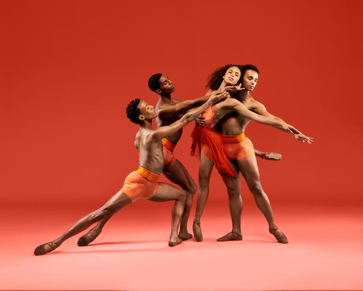 Four Dance Theatre of Harlem dancers perform together in front of an orange background.