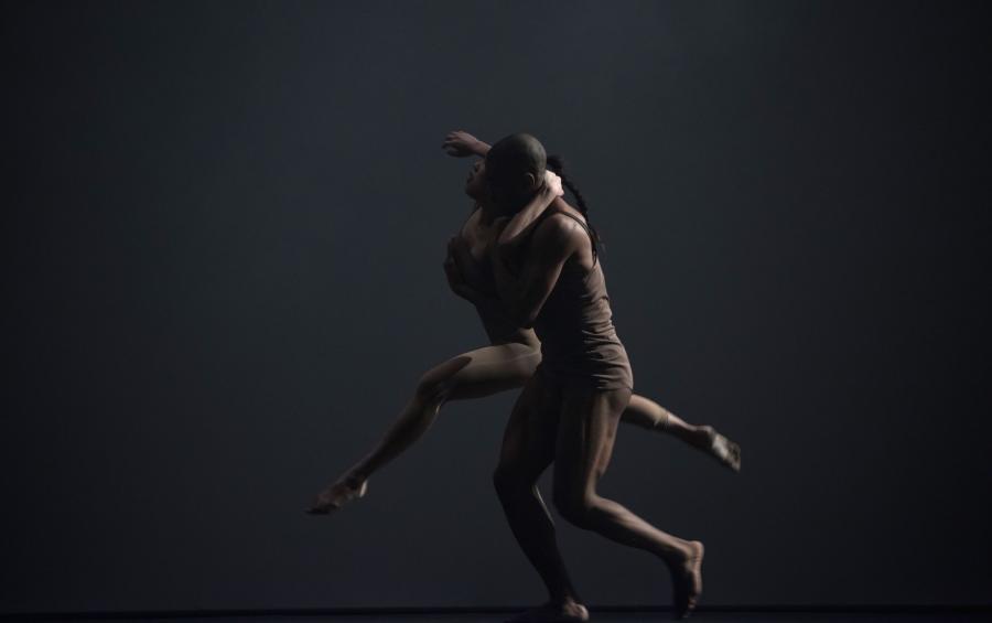 He is mid-stride holding his partner as she leaps, her arm around his neck