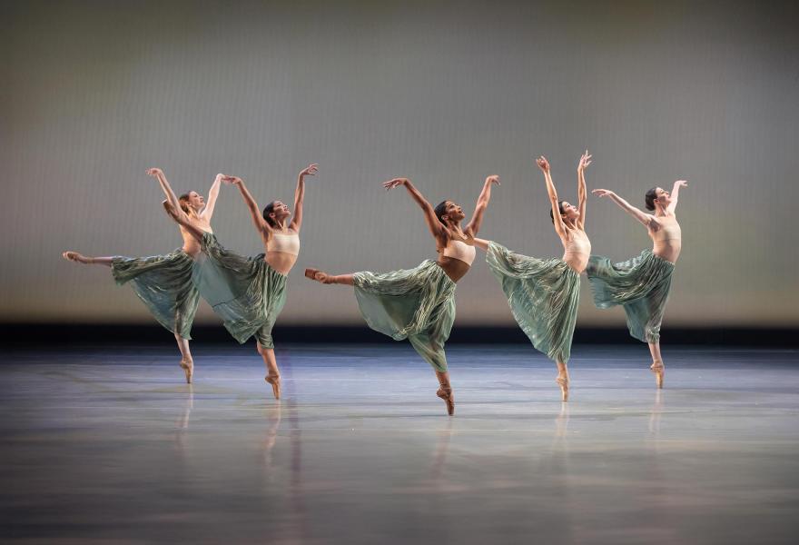 Ballet dancers in green skirts dance in unison.