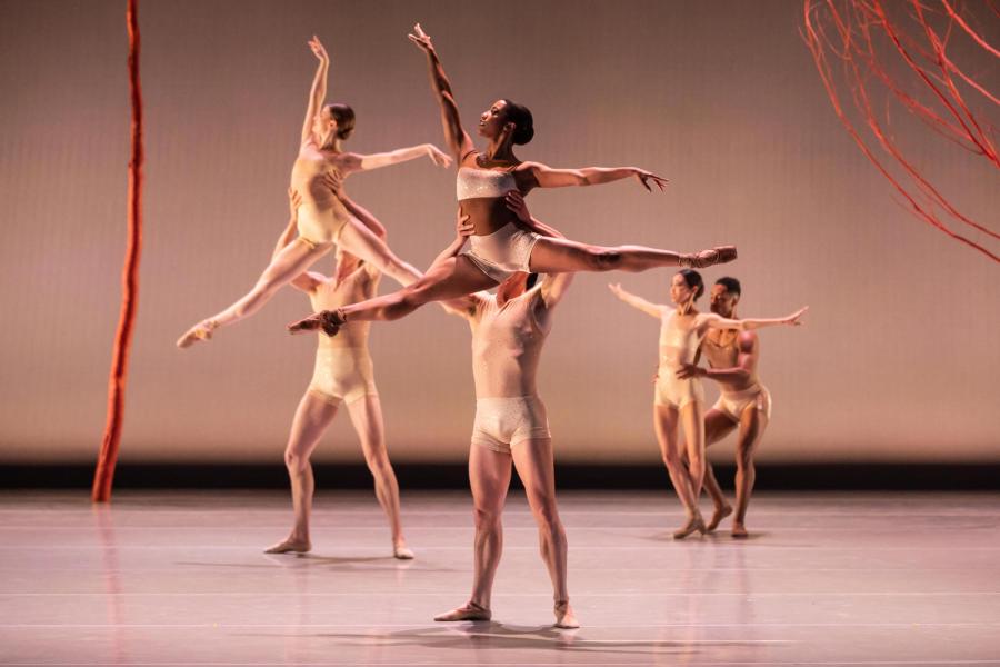 Ballet dancers in tan costumes paired and doing lifts.