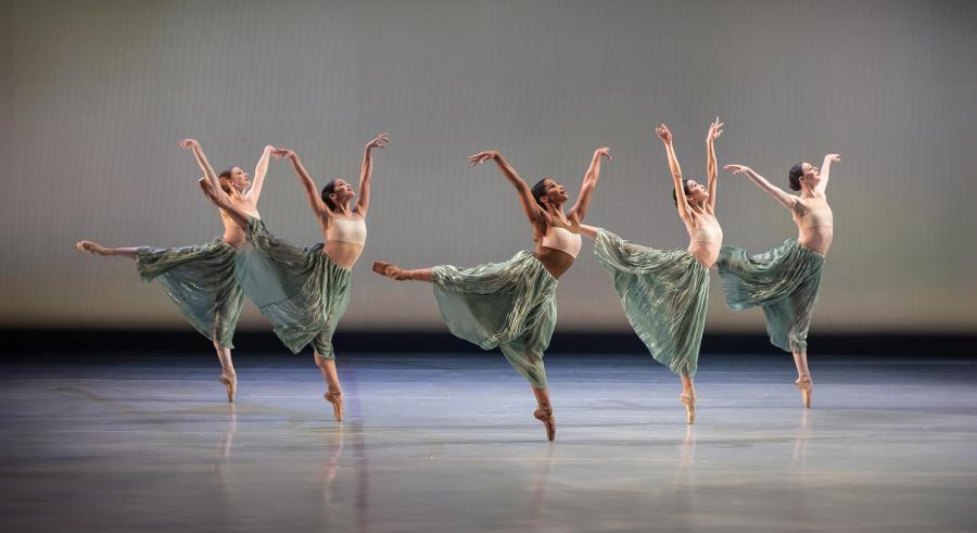Ballet dancers in green skirts on a sparse stage.