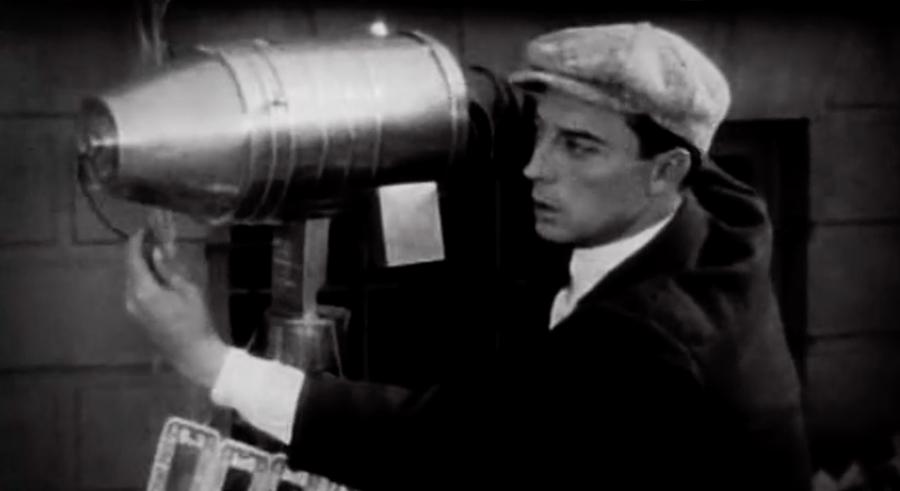 Buster Keaton fiddles with a metallic instrument in a still from The Cameraman.