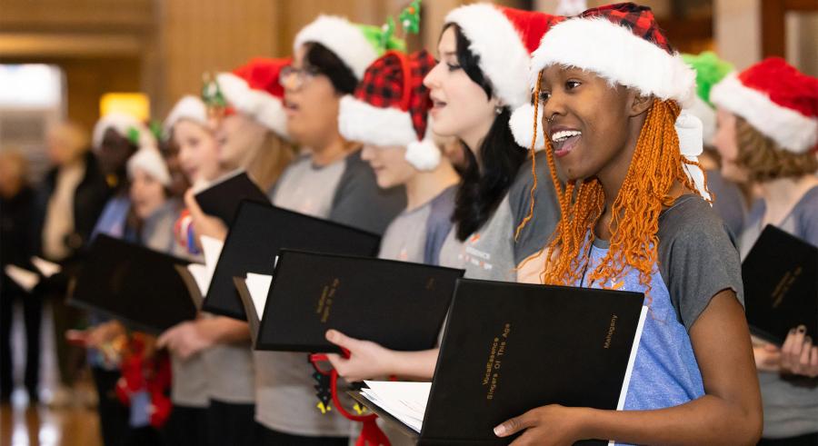 Young VocalEssence members perform carols wearing Santa hats.