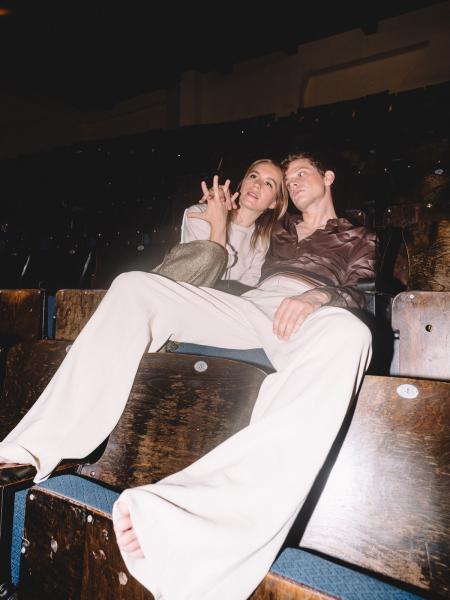 Perfume Genius and Kate Wallich sitting in a theater holding hands