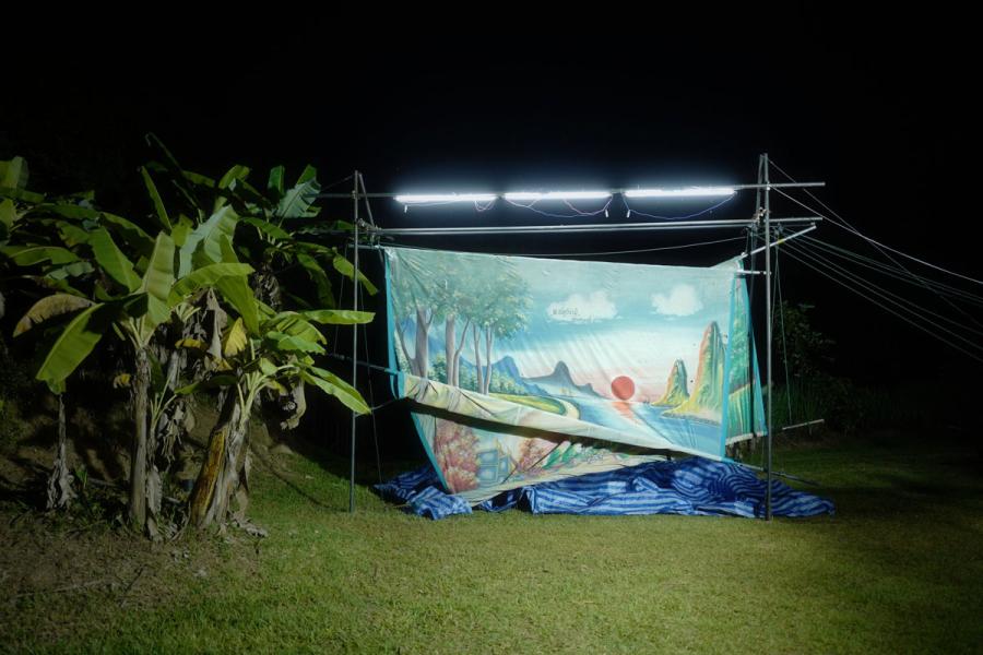 Production backdrops half unfurled under light next to a palm tree