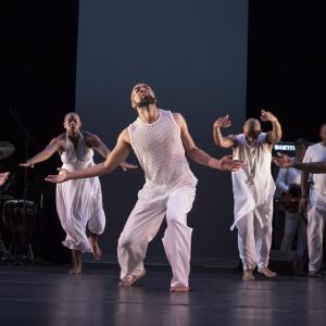 A group of dancers wearing all white perform on stage.