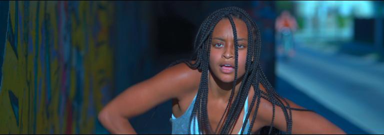 Hubbard Street Dance film still - woman with brown skin, braided hair wearing a light blue tank top