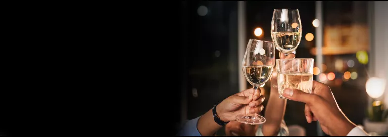 Close-up of hands toasting with wine and cocktail glasses