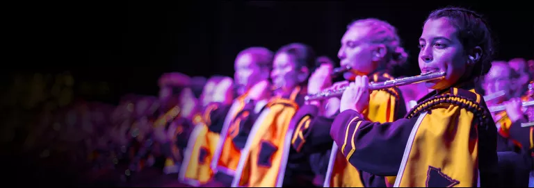 Line of flutists performing on a stage.