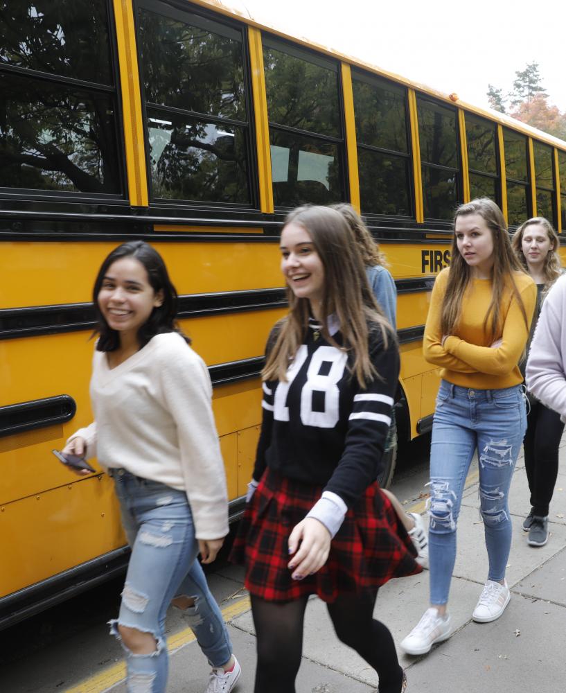 students in line for a bus smiling