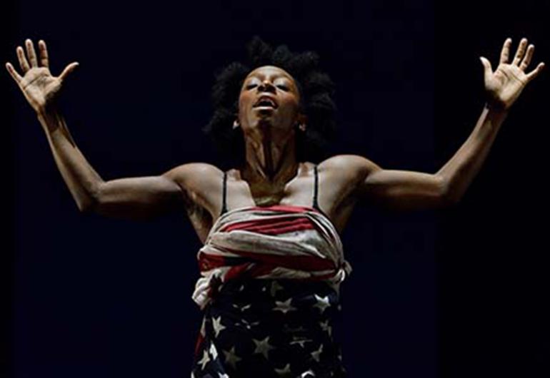 Alanna Morris wears a top made from an American Flag has her hands up and head back with eyes closed and mouth open