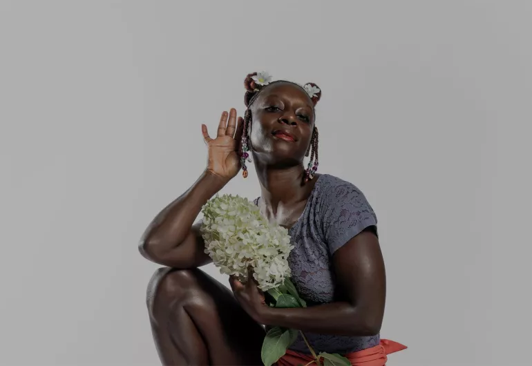 Morris holds her hand to her ear, eyes closed and hugs a boquet of white flowers to her chest