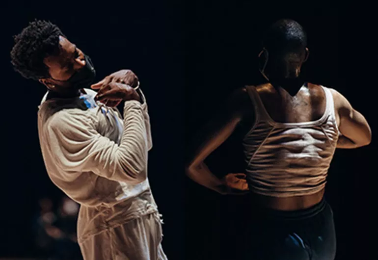 One dancer in light, masked and hands pointing to his chest, a second dancer in shadow back to us, arms bent forward