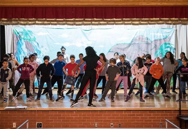 A full class of kids of varying ages learning to dance