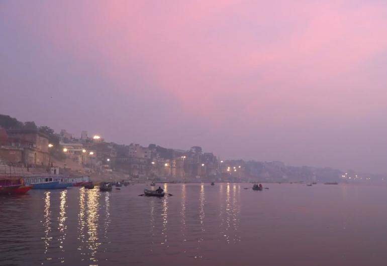 The river's edge of Varanasi under a pink sky
