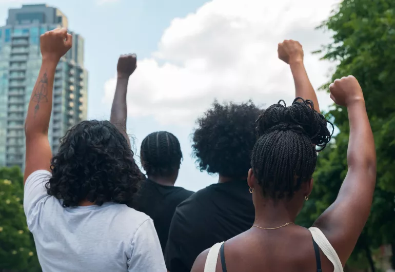 View from behind of people raising a fist in the air