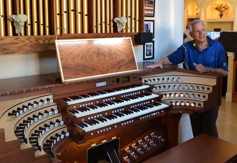 Hector Olivera standing behind a full concert organ
