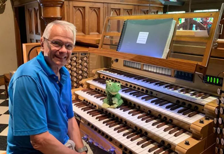 Hector sits at the organ and a frog plush toy sits on the keyboard