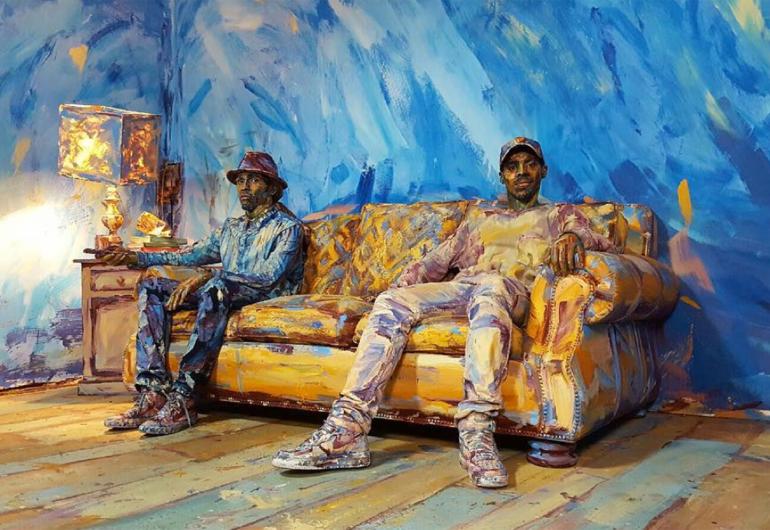 Jon Boogz and Lil Buck sit on a couch in a painted room in the video "Color of Reality".