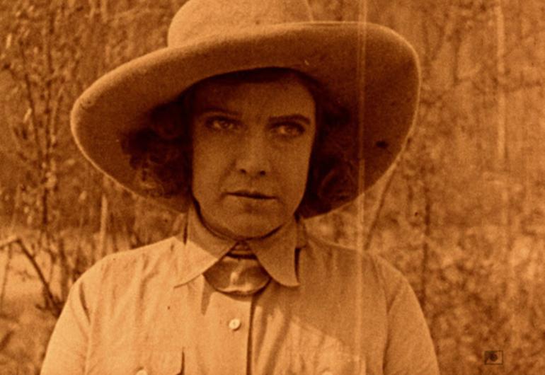 Sepia-toned image of women scowling wearing a cowboy hat.