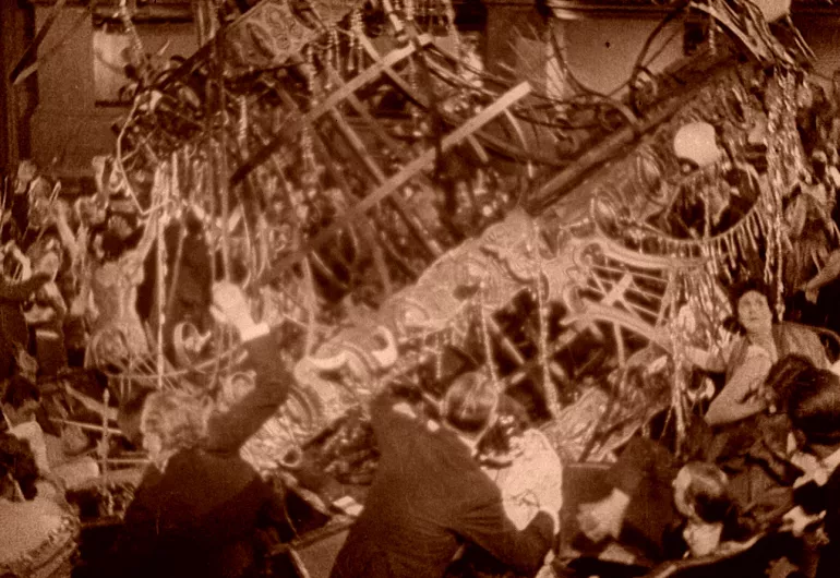 Film still of a chandelier crashing down on the audience