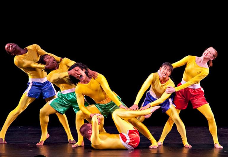 Pilobolus in yellow bodysuits and colorful athletic shorts