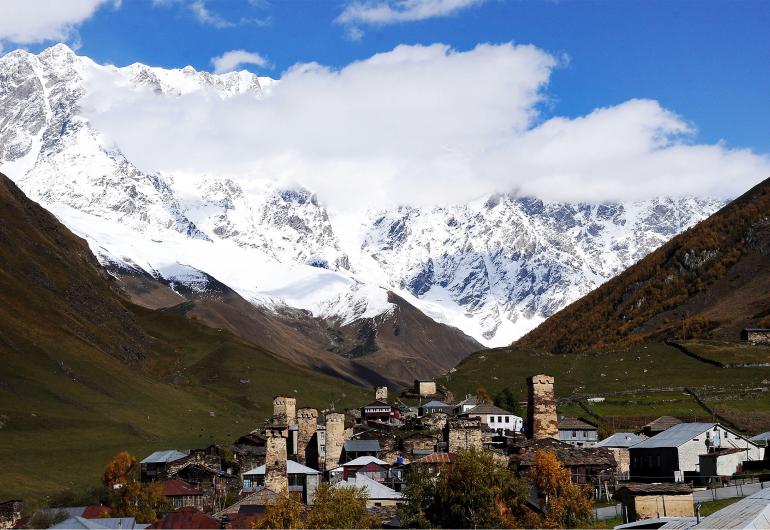 Svaneti, Georgia - a cluster a stone buildings nestled in a valley below snow covered mountains
