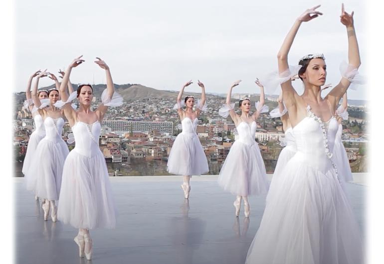 Ballerina dance on a rooftop with the hills and city in the distance