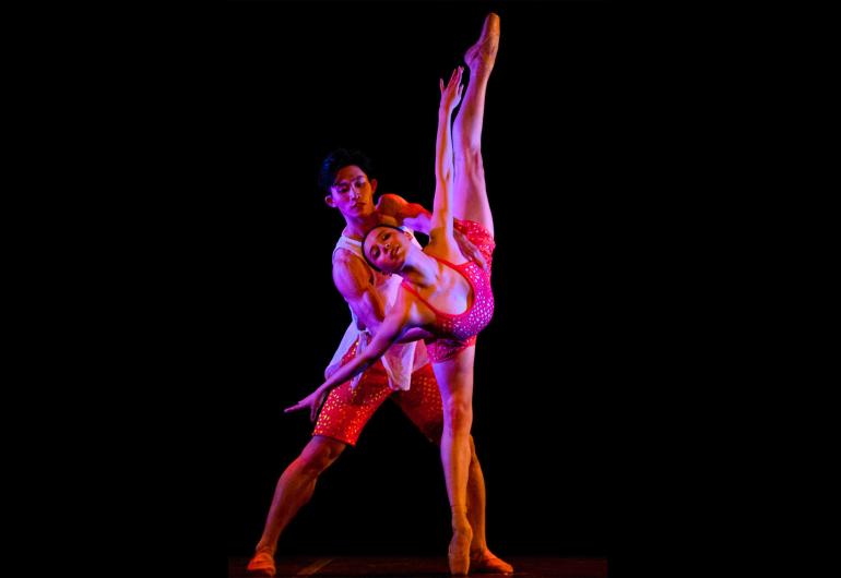 Two dancers pair in a pink orange light and black background
