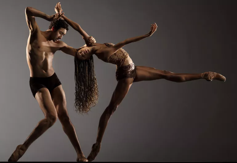 Photo © RJ Muna. Two dancers in front of a gray backdrop, a man and a woman, dancing in Alonzo King and LINES Ballet's Deep River.