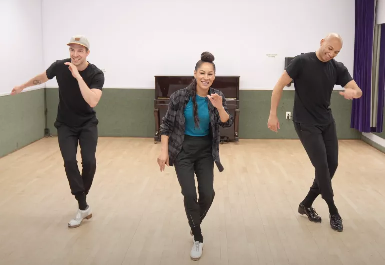 Casel dances with two men in a studio setting