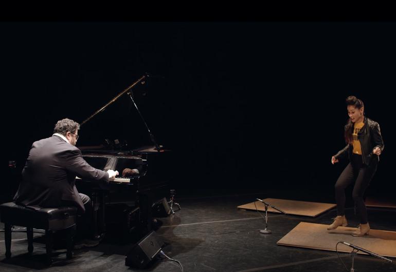 Casel dancing on a stage, accompanied by a pianist sitting at a piano near her.