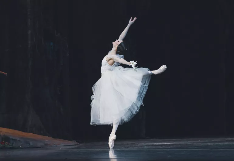 Single ballerina in white does an arabesque