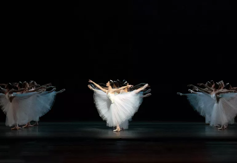 Three synchronized clusters of dancers strike the same pose at once.