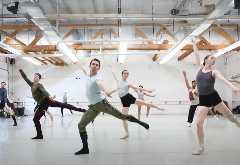 Several BalletMet dancers in athletic clothing rehearse in a studio.