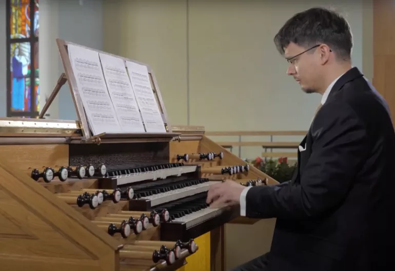 Filip Presseisen, a man wearing a suit, plays the organ in a church.