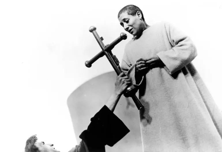 A friar holds up a cross for Joan of Arc to see before she is burned at the stake.