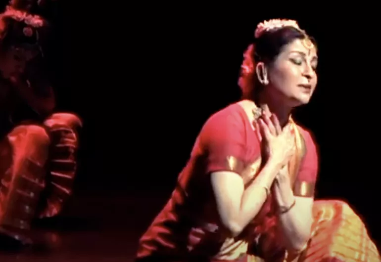 video still of Ranee Ramaswamy performing, eyes closed, hands crossed at her chest