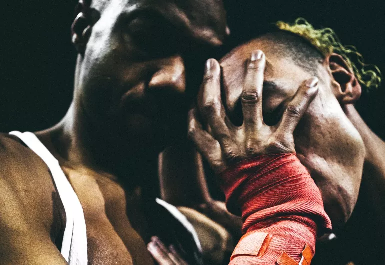 One man palms the face of the other.