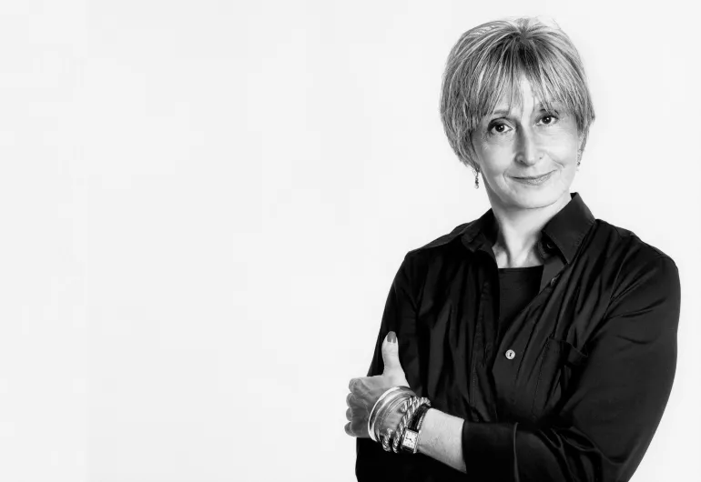 Dance choreographer Twyla Tharp, a woman with short hair, is wearing a black shirt and smiling into the camera.