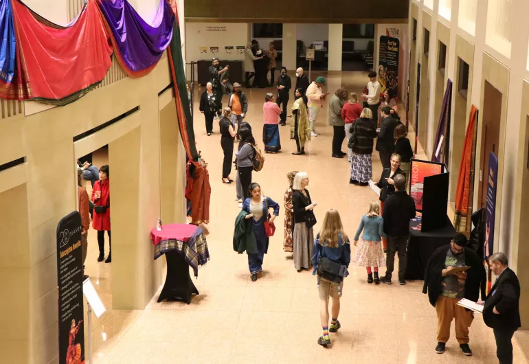 People mingle in the Northrop lobby, where colorful fabric art is exhibited.