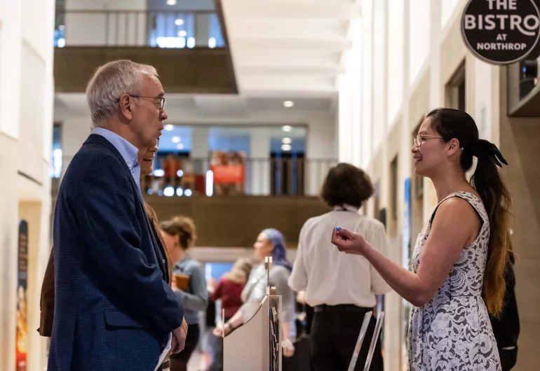Two people face each other while talking in the Northrop lobby.