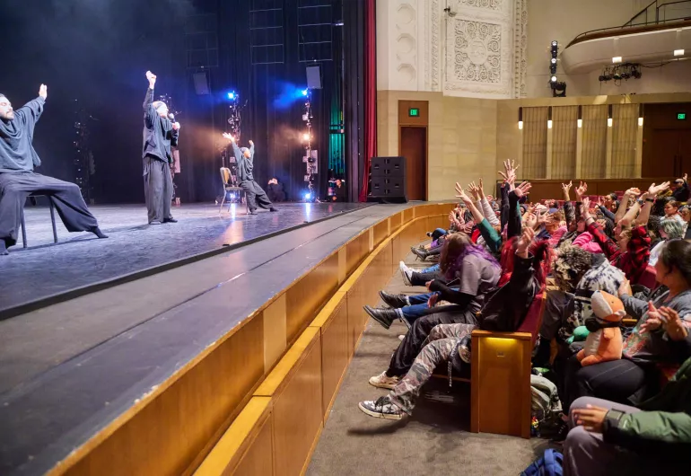 Students in the audience follow along with the dancers on stage.