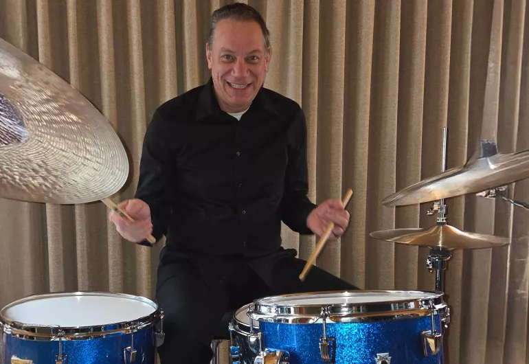 A grinning Steve Kimball sits at his drum kit.