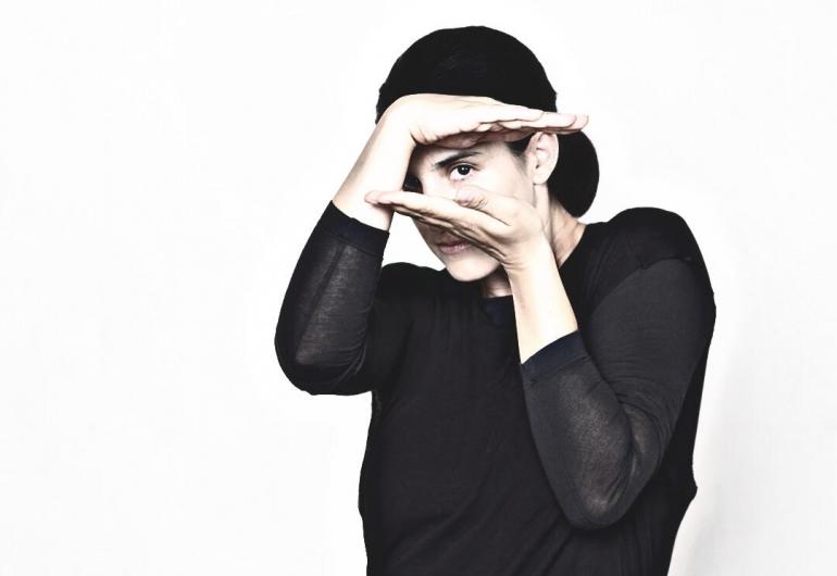 Andrea Miller in a black shirt looking through her hands in a square shape
